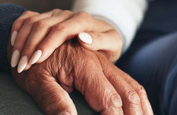 Close up of two hands on top of each other resting on someone